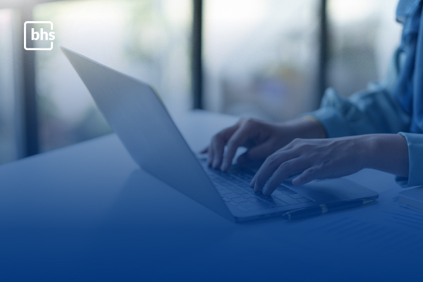 Pessoa utilizando notebook para configuração de eDiscovery e conformidade regulatória no Microsoft 365, com marca d'água da BHS em ambiente corporativo.